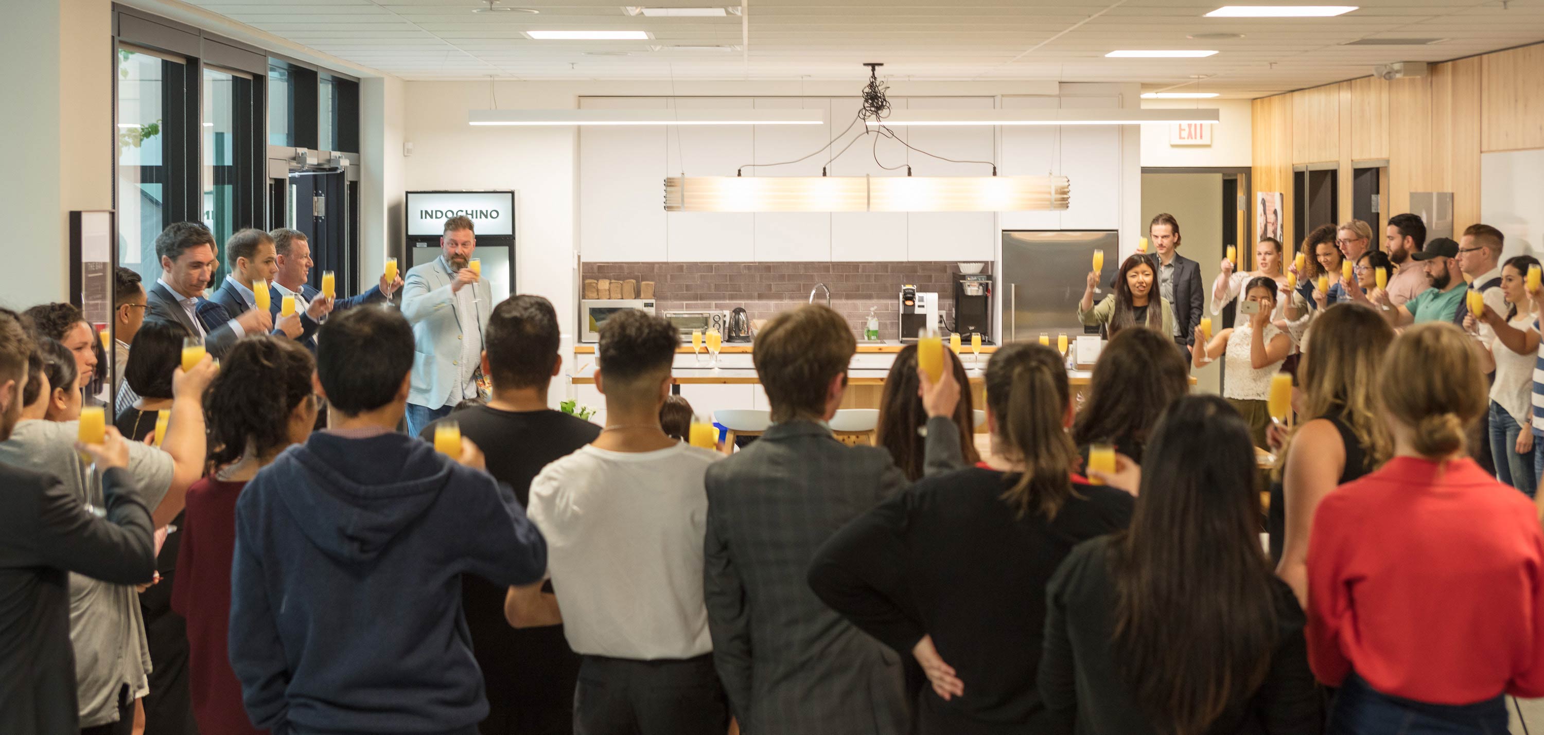 INDOCHINO employees raising a toast in the luchroom at headquarters.